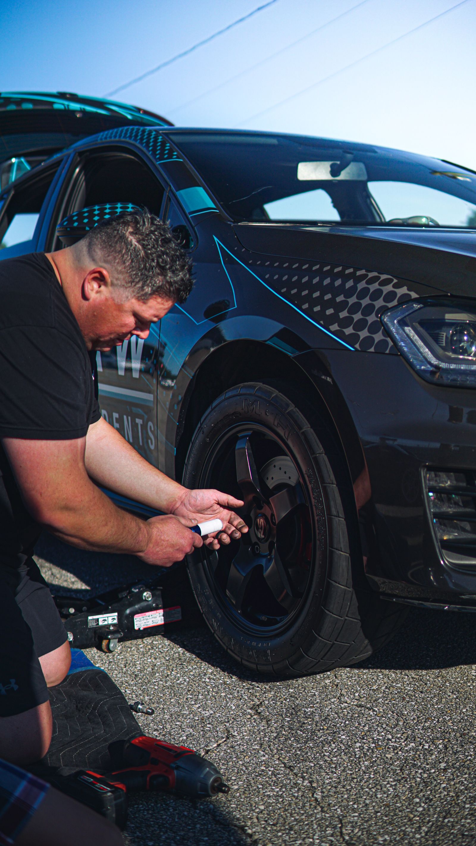 Driver changing a tire beside a car